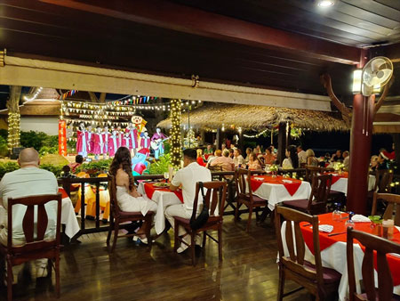 Guests Enjoying Children Carolers While Having Christmas Eve Dinner