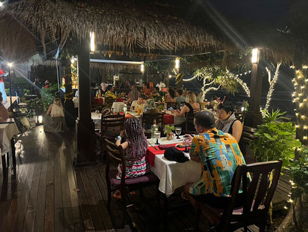 Guests enjoying Christmas Eve dinner while children carolers sing