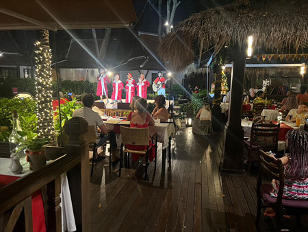 Children carolers on stage; guests enjoying dinner